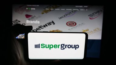 Stuttgart, Almanya - 10-11-2025: İnternet sayfası önünde spor bahisleri şirketi Super Group logosu olan cep telefonu sahibi kişi. Telefon ekranına odaklan.