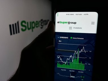 Stuttgart, Almanya - 10-11-2025: Spor bahisleri şirketi Super Group 'un web sayfası olan akıllı telefon sahibi kişi logonun önünde ekranda. Telefon ekranının merkezine odaklan.