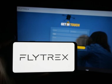 Stuttgart, Almanya - 10-11-2025: İHA gıda dağıtım şirketi Flytrex Inc. 'in logosunu elinde tutan kişi web sitesinin önünde ekranda. Telefon ekranına odaklan.