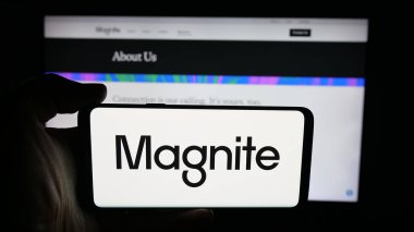 Stuttgart, Almanya - 10-12-2025: İnternet sayfasının önünde ABD 'li online reklam şirketi Magnite Inc.' in logosuyla cep telefonu tutan kişi. Telefon ekranına odaklan.
