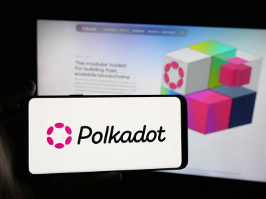 Stuttgart, Almanya - 10-13-2025: Web sitesi önünde ekranda engelleme şirketi Polkadot 'nun logosuna sahip akıllı telefonu tutan kişi. Telefon ekranına odaklan.