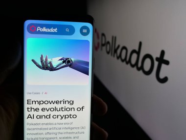 Stuttgart, Almanya - 10-13-2025: Logo önündeki ekranda, engelleme şirketi Polkadot 'nun (Dikkat dağıtma şirketi) web sayfası olan akıllı telefon sahibi kişi. Telefon ekranının merkezine odaklan.