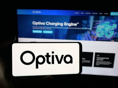 Stuttgart, Almanya - 10-13-2025: İnternet sitesinin önünde ekranda telekomünikasyon şirketi Optiva Inc. 'in logosunun bulunduğu akıllı telefonu tutan kişi. Telefon ekranına odaklan.