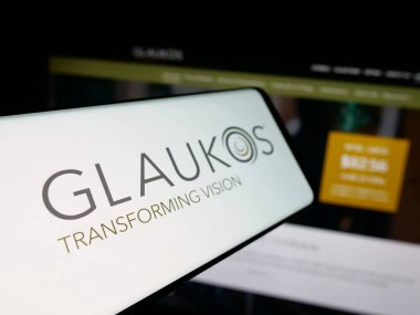 Stuttgart, Almanya - 10-13-2025: İnternet sitesinin önünde ekranda Glaukos Corporation adlı ABD 'li oftalmik şirketin logosuna sahip akıllı telefon. Telefon ekranının soluna odaklan.