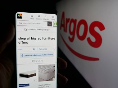 Stuttgart, Almanya - 10-15-2025: İngiliz perakende şirketi Argos Limited 'in web sayfası ile akıllı telefon sahibi kişi logonun önünde ekranda. Telefon ekranının merkezine odaklan.