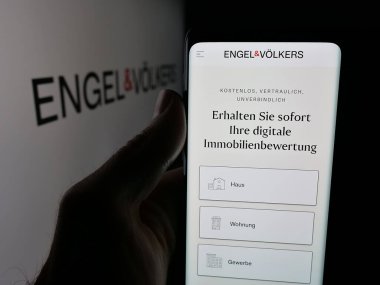 Stuttgart, Almanya - 10-15-2025: Alman emlak şirketi Engel ve Voelkers 'ın internet sayfası olan cep telefonu logosu önünde ekranda. Telefon ekranının merkezine odaklan.