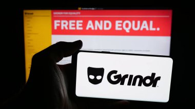 Stuttgart, Almanya - 10-15-2025: Cep telefonunda LGBT sosyal medya platformu şirketi Grindr Inc 'in logosu olan kişi web sayfasının önünde ekranda. Telefon ekranına odaklan.