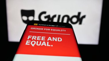 Stuttgart, Almanya - 10-15-2025: Logo önünde ekranda LGBT sosyal medya platformu şirketi Grindr Inc 'in web sitesi bulunan cep telefonu. Telefon ekranının sol üst kısmına odaklan.