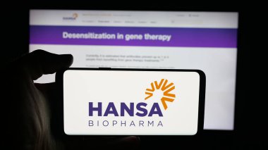 Stuttgart, Almanya - 10-16-2025: İsveçli Hansa Biopharma AB şirketinin logosuyla cep telefonu sahibi kişi web sayfasının önünde ekranda. Telefon ekranına odaklan.