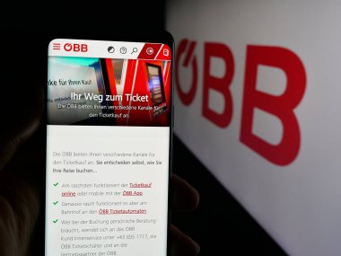 Stuttgart, Almanya - 10-17-2025: Demiryolu şirketi Oesterreichische Bundesbahnen 'in web sitesi ile cep telefonu tutan kişi logonun önünde ekranda. Telefon ekranının merkezine odaklan.