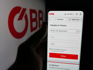 Stuttgart, Almanya - 10-17-2025: Demiryolu şirketi Oesterreichische Bundesbahnen 'in web sitesi ile akıllı telefon sahibi kişi logonun önünde ekranda. Telefon ekranının merkezine odaklan.