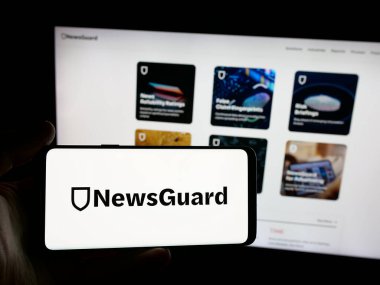 Stuttgart, Almanya - 10-17-2025: Haber derecelendirme şirketi NewsGuard Technologies 'in logosunu elinde tutan kişi web sitesinin önünde ekranda. Telefon ekranına odaklan.