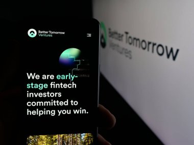 Stuttgart, Almanya - 10-18-2025: ABD 'li şirket Better Tomorrow Ventures' in (BTV) web sayfası ile logo önünde cep telefonu tutan kişi. Telefon ekranının merkezine odaklan.