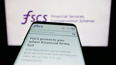 Stuttgart, Almanya - 10-18-2025: Finansal Hizmetler Tazminat Şeması (FSCS) web sitesi ile birlikte logo önünde cep telefonu. Telefon ekranının sol üst kısmına odaklan.
