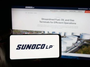 Stuttgart, Almanya - 10-18-2025: ABD 'li petrol şirketi Sunoco LP' nin logosuna sahip akıllı telefon sahibi kişi web sitesinin önünde ekranda. Telefon ekranına odaklan.