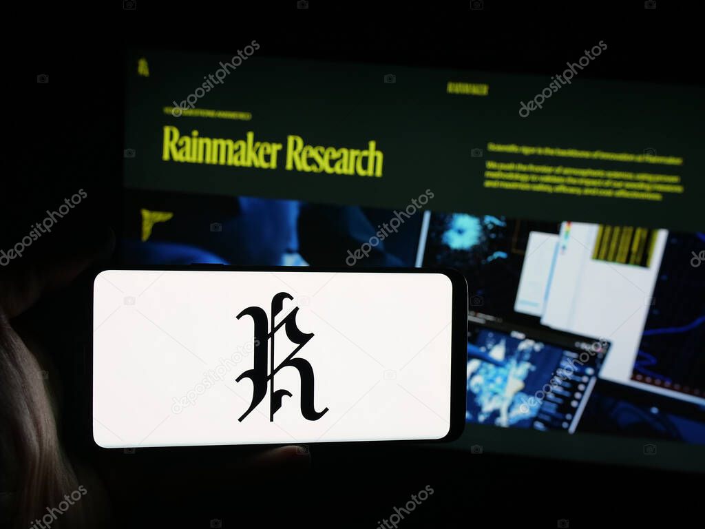 Stuttgart, Germany - 10-15-2025: Person holding smartphone with logo of cloud seeding company Rainmaker Technology on screen in front of website. Focus on phone display.