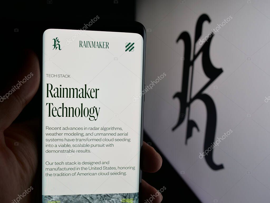Stuttgart, Germany - 10-15-2025: Person holding cellphone with webpage of cloud seeding company Rainmaker Technology on screen in front of logo. Focus on center of phone display.