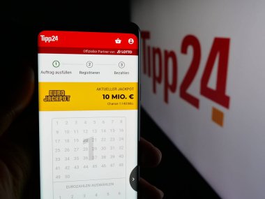 Stuttgart, Almanya - 10-19-2025: Alman çevrimiçi piyango şirketi Tipp24.de 'nin internet sayfası olan cep telefonu logonun önünde ekranda. Telefon ekranının merkezine odaklan.