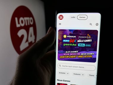Stuttgart, Almanya - 10-19-2025: Logo önündeki ekranda Alman piyango şirketi Lotto24 AG 'nin internet sayfası ile akıllı telefon tutan kişi. Telefon ekranının merkezine odaklan.