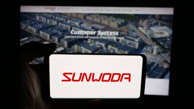 Stuttgart, Almanya - 10-19-2025: Çinli şirket Sunwoda Electronic Co. Ltd. nin logosuyla cep telefonu sahibi kişi web sayfasının önünde ekranda. Telefon ekranına odaklan.