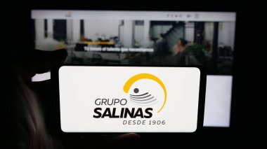 Stuttgart, Almanya - 10-20-2025: Cep telefonunda Meksika holdingi Grupo Salinas 'ın logosu olan kişi web sayfasının önünde ekranda. Telefon ekranına odaklan.