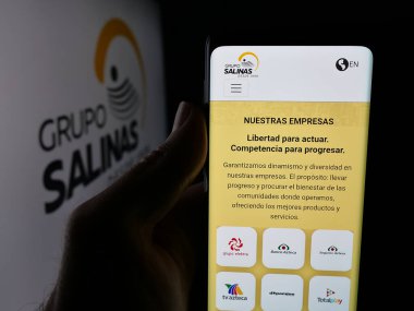 Stuttgart, Almanya - 10-20-2025: Meksika holdingi Grupo Salinas 'ın web sayfası olan akıllı telefonu logonun önünde tutan kişi. Telefon ekranının merkezine odaklan.