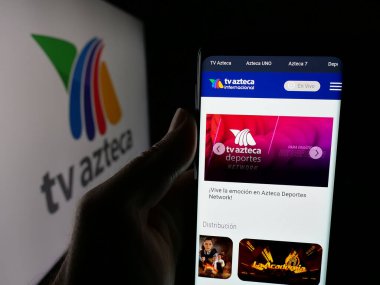 Stuttgart, Almanya - 10-20-2025: Meksikalı televizyon şirketi Azteca 'nın web sayfası olan akıllı telefonu logonun önünde ekranda tutan kişi. Telefon ekranının merkezine odaklan.
