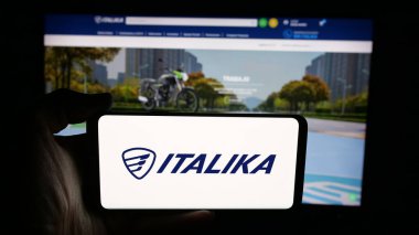 Stuttgart, Almanya - 10-20-2025: Cep telefonunda Meksikalı motosiklet şirketi Italika 'nın logosu olan kişi web sayfasının önünde ekranda. Telefon ekranına odaklan.