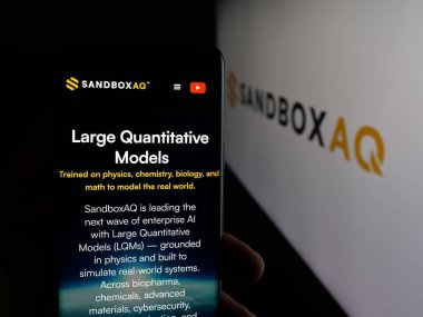 Stuttgart, Almanya - 10-20-2025: ABD 'li SB Technology Inc. (SandboxAQ) şirketinin web sayfası logonun önünde duran kişi. Telefon ekranının merkezine odaklan.