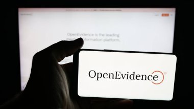 Stuttgart, Almanya - 10-22-2025: Web sayfasının önünde ekranda ABD 'li tıbbi yapay zeka şirketi OpenEvidence Inc.' nin logosunun bulunduğu cep telefonu sahibi kişi. Telefon ekranına odaklan.