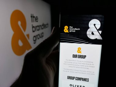 Stuttgart, Almanya - 10-22-2025: ABD 'li pazarlama şirketi The Brandtech Group LLC' nin web sayfası ile akıllı telefon sahibi kişi logonun önünde ekranda. Telefon ekranının merkezine odaklan.
