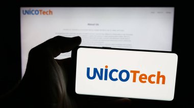 Stuttgart, Almanya - 10-24-2025: Web sayfasının önünde ekranda AI yatırım şirketi UnicoTech Inc. 'in logosuna sahip cep telefonu tutan kişi. Telefon ekranına odaklan.
