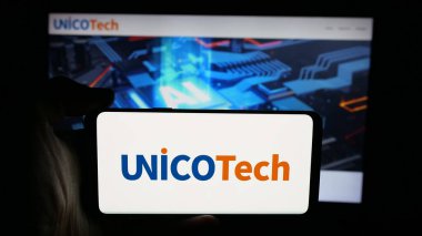 Stuttgart, Almanya - 10-24-2025: Web sayfasının önünde AI yatırım şirketi UnicoTech Inc. 'in logosunun bulunduğu cep telefonu sahibi kişi. Telefon ekranına odaklan.