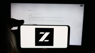 Stuttgart, Almanya - 10-24-2025: İnternet sayfası önünde ekranda Beijing Zhipu Huazhang Technology (Zai) logosu bulunan kişi. Telefon ekranına odaklan.