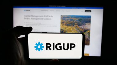 Stuttgart, Almanya - 10-24-2025: İnternet sayfasının önünde ABD 'li enerji yazılım şirketi RigUp Inc.' in logosuyla cep telefonu tutan kişi. Telefon ekranına odaklan.