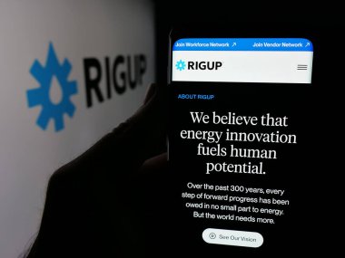 Stuttgart, Almanya - 10-24-2025: ABD 'li enerji yazılım şirketi RigUp Inc.' in web sayfası ile akıllı telefon sahibi kişi logonun önünde ekranda. Telefon ekranının merkezine odaklan.