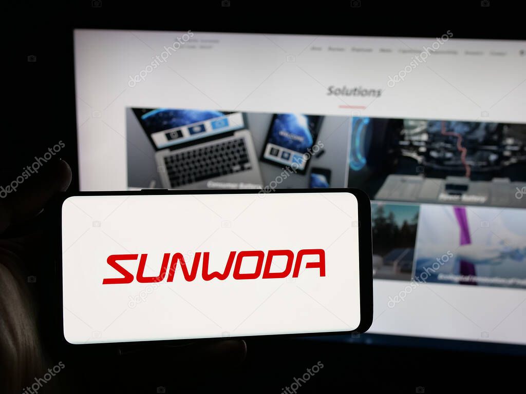 Stuttgart, Germany - 10-19-2025: Person holding smartphone with logo of Chinese company Sunwoda Electronic Co. Ltd. on screen in front of website. Focus on phone display.