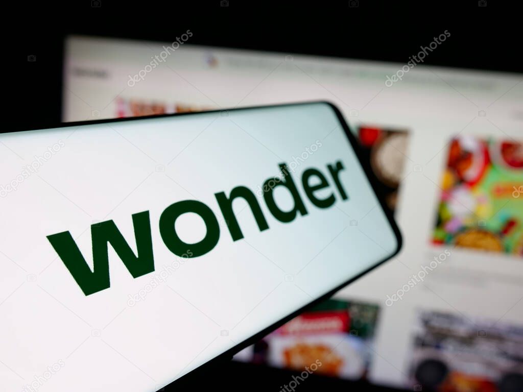 Stuttgart, Germany - 10-20-2025: Smartphone with logo of US food delivery company Wonder Group Inc. on screen in front of website. Focus on center-left of phone display.