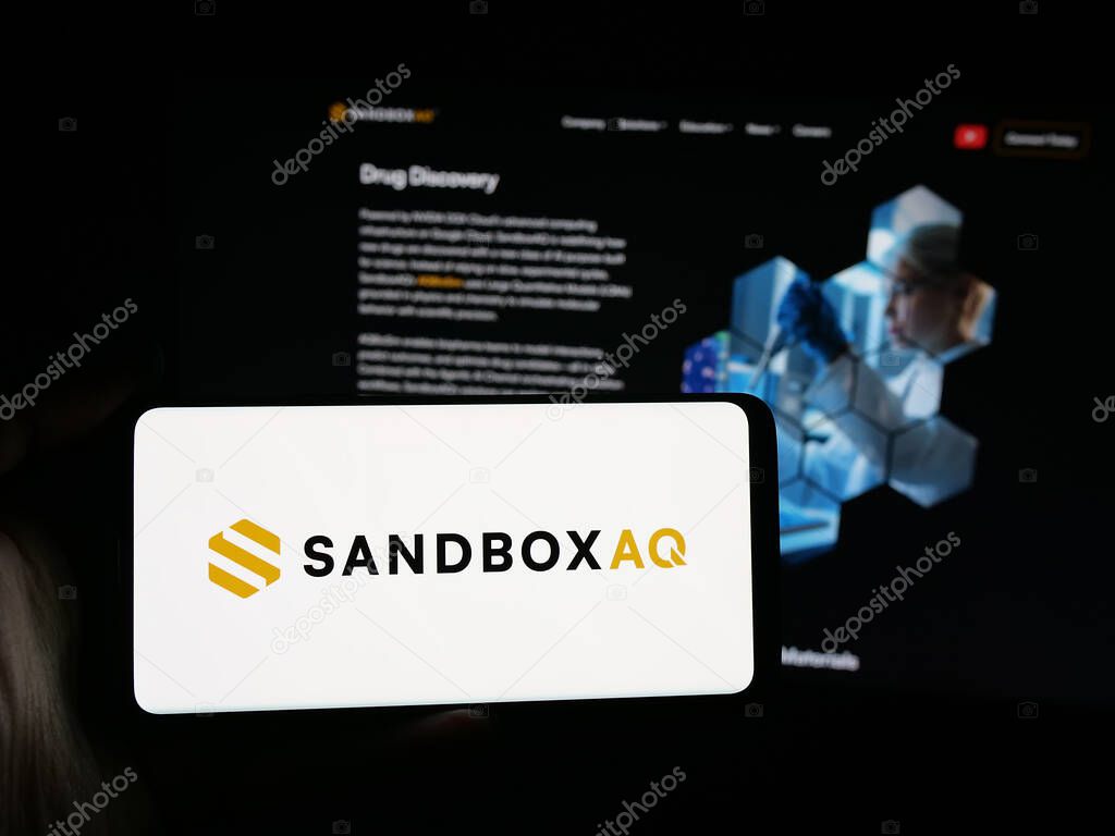 Stuttgart, Germany - 10-20-2025: Person holding smartphone with logo of US company SB Technology Inc. (SandboxAQ) on screen in front of website. Focus on phone display.