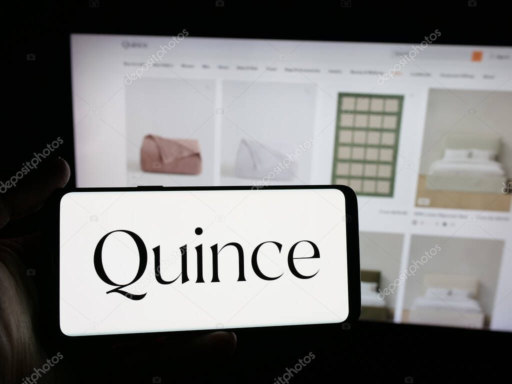 Stuttgart, Germany - 10-20-2025: Person holding smartphone with logo of US fashion company Last Brand Inc. (Quince) on screen in front of website. Focus on phone display.