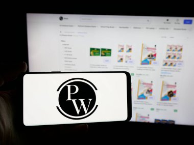 Stuttgart, Almanya - 10-25-2025: Hintli şirket Physics Wallah Limited (PW) logosuna sahip akıllı telefon sahibi kişi web sitesinin önünde ekranda. Telefon ekranına odaklan.
