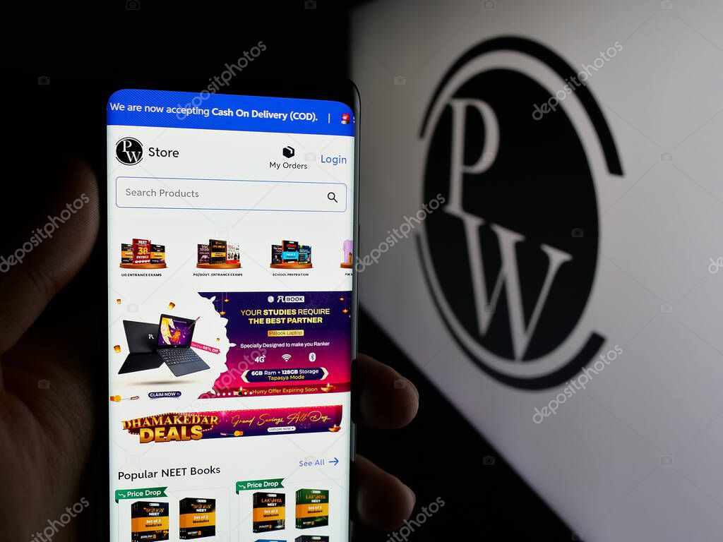 Stuttgart, Germany - 10-25-2025: Person holding cellphone with webpage of Indian company Physics Wallah Limited (PW) on screen in front of logo. Focus on center of phone display.