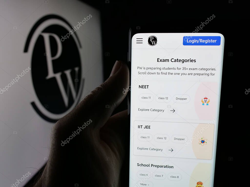 Stuttgart, Germany - 10-25-2025: Person holding smartphone with web page of Indian company Physics Wallah Limited (PW) on screen in front of logo. Focus on center of phone display.