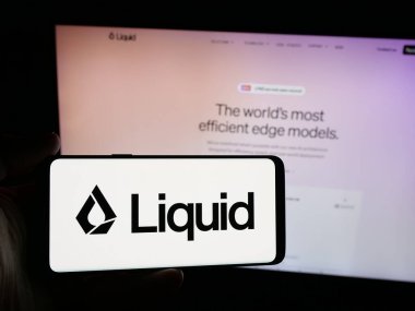 Stuttgart, Almanya - 10-27-2025: ABD 'li yapay zeka şirketi Liquid AI' ın logosunu elinde tutan kişi web sitesinin önünde ekranda. Telefon ekranına odaklan.