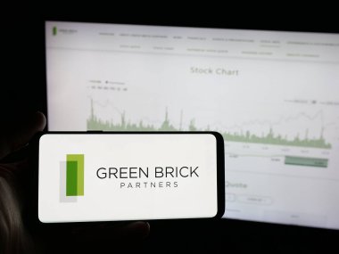 Stuttgart, Almanya - 10-27-2025: Web sitesinin önünde üzerinde ev yapımı şirketi Green Brick Partners Inc. 'in logosu bulunan akıllı telefon sahibi kişi. Telefon ekranına odaklan.