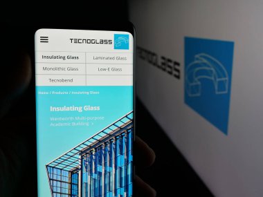 Stuttgart, Almanya - 10-30-2025: Mimari cam şirketi Tecnoglass Inc. 'in web sayfası ile akıllı telefon sahibi kişi logonun önünde ekranda. Telefon ekranının merkezine odaklan.
