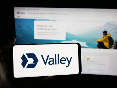 Stuttgart, Almanya - 10-30-2025: ABD 'li finans şirketi Valley National Bank' ın logosunu elinde tutan kişi web sitesinin önünde ekranda. Telefon ekranına odaklan.