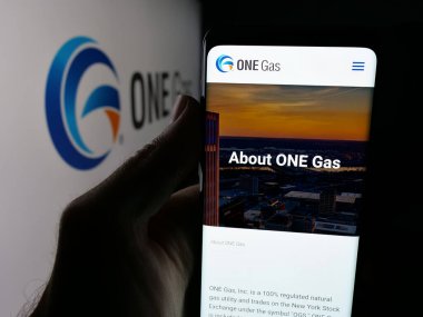 Stuttgart, Almanya - 10-30-2025: ABD 'li doğalgaz şirketi One Gas Inc.' in web sayfası ile akıllı telefon sahibi kişi logonun önünde ekranda. Telefon ekranının merkezine odaklan.