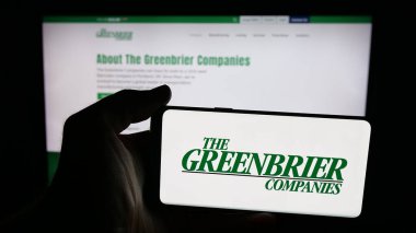 Stuttgart, Almanya - 10-30-2025: İçinde demiryolu şirketi The Greenbrier Company 'nin logosu olan cep telefonu sahibi kişi web sayfasının önünde ekranda. Telefon ekranına odaklan.