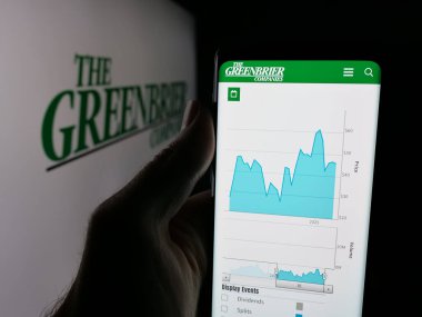 Stuttgart, Almanya - 10-30-2025: Demiryolu şirketi The Greenbrier Companies Inc. 'in web sayfası ile akıllı telefon sahibi kişi logonun önünde ekranda. Telefon ekranının merkezine odaklan.